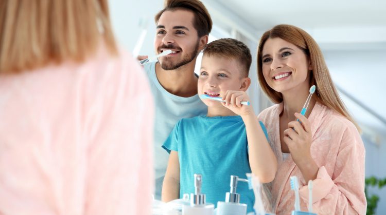 Smiling family brushing teeth together to prevent cavities in kids – Palo Verde Smiles
